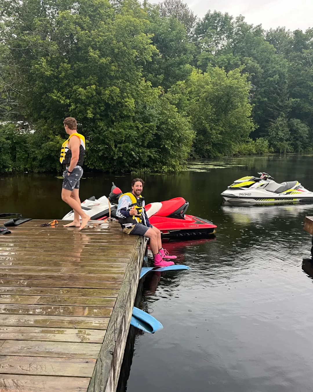 Two Flyboard team members preparing beside personal watercraft at a dock