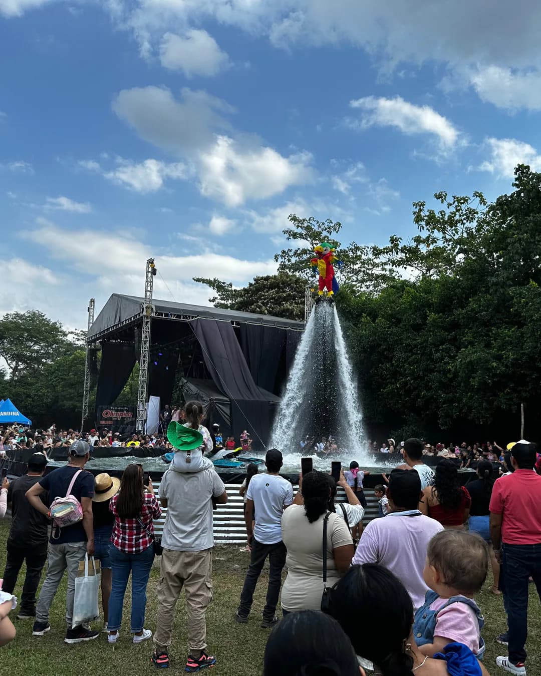 Crowd watching a costumed Flyboard performer above an outdoor event pool