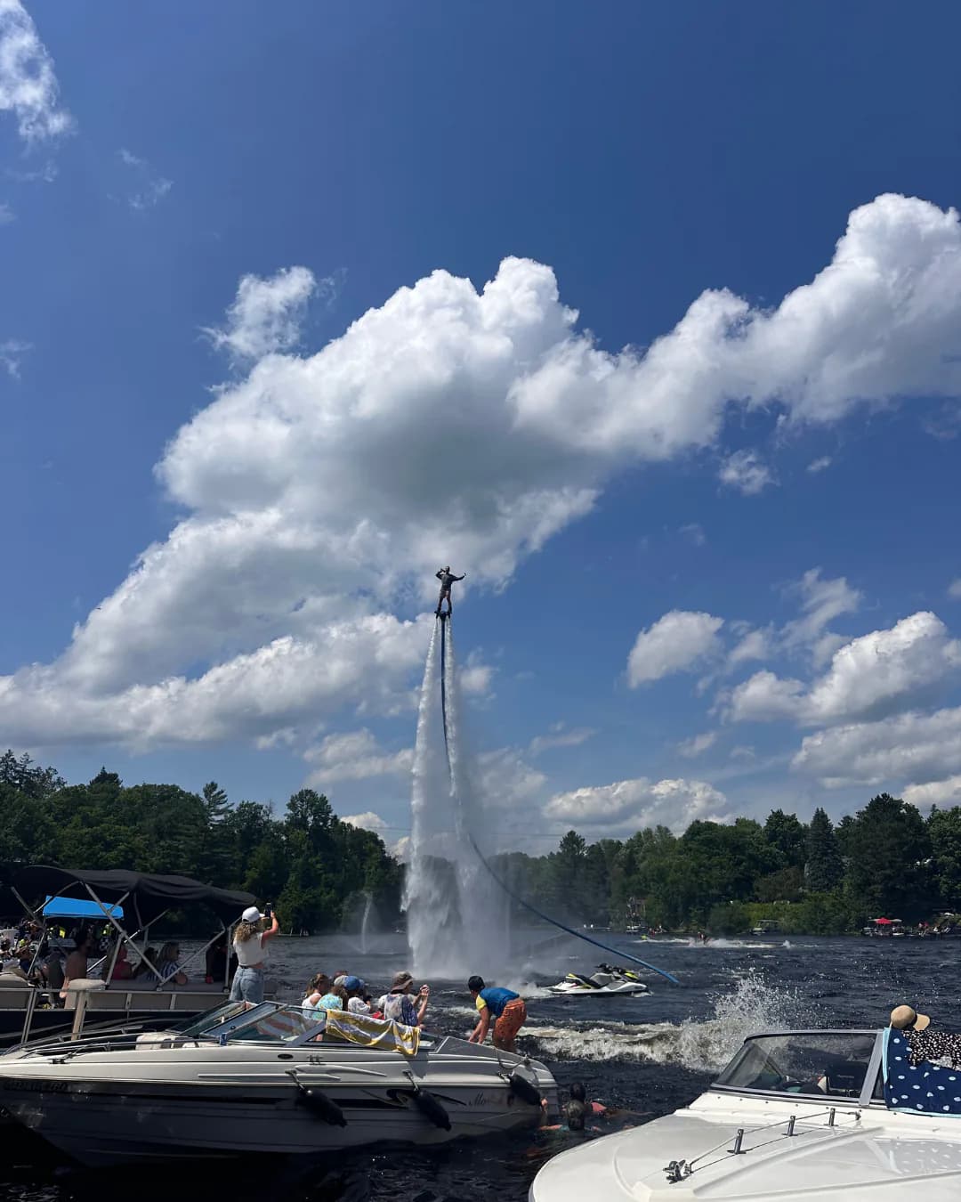 Flyboard performer flying high above a Huntsville waterfront as boaters watch