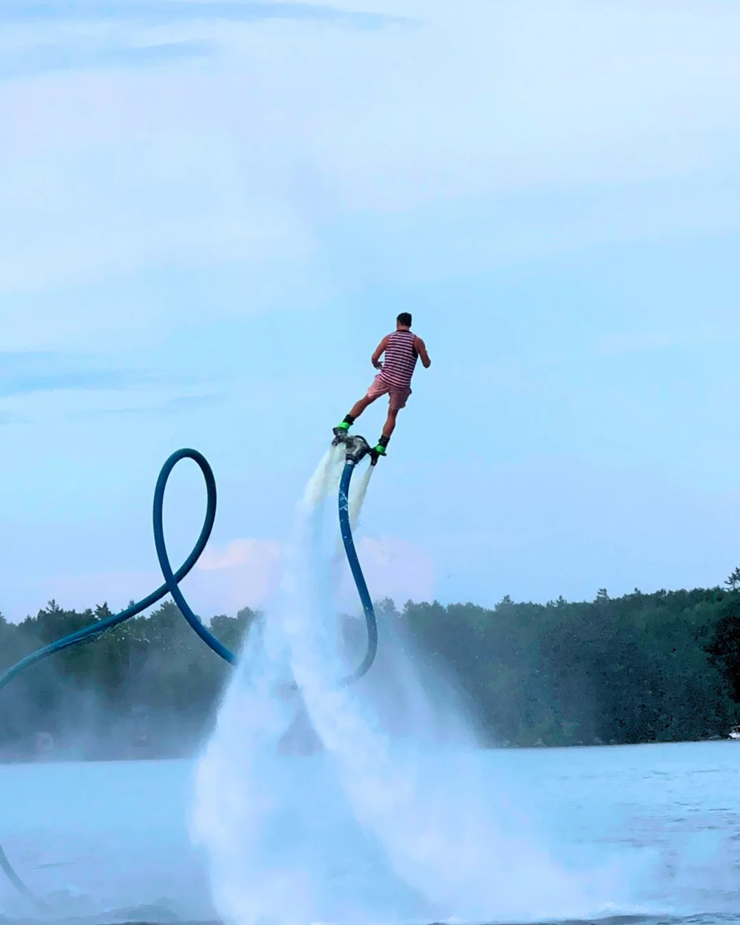 Flyboard performer flying beside a large loop formed by the Flyboard hose