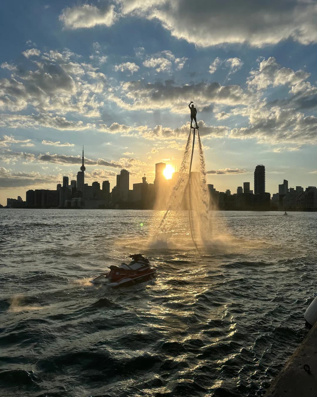 Flyboard performer flying at sunset with the Toronto skyline behind him