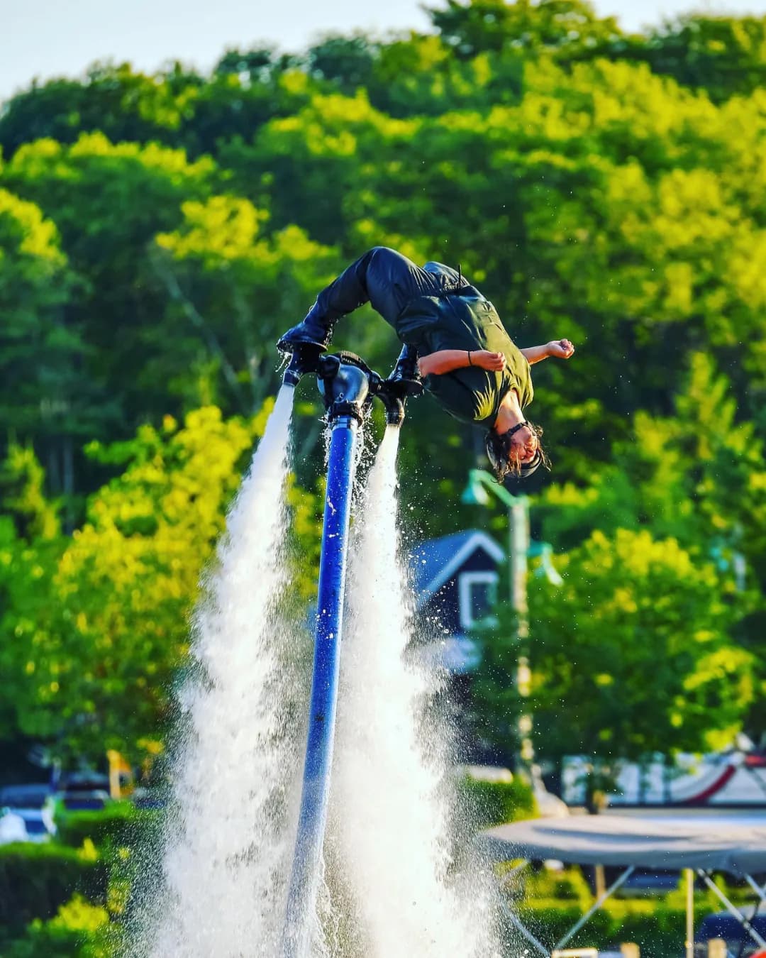 Flyboard performer executing a backflip above a waterfront wharf