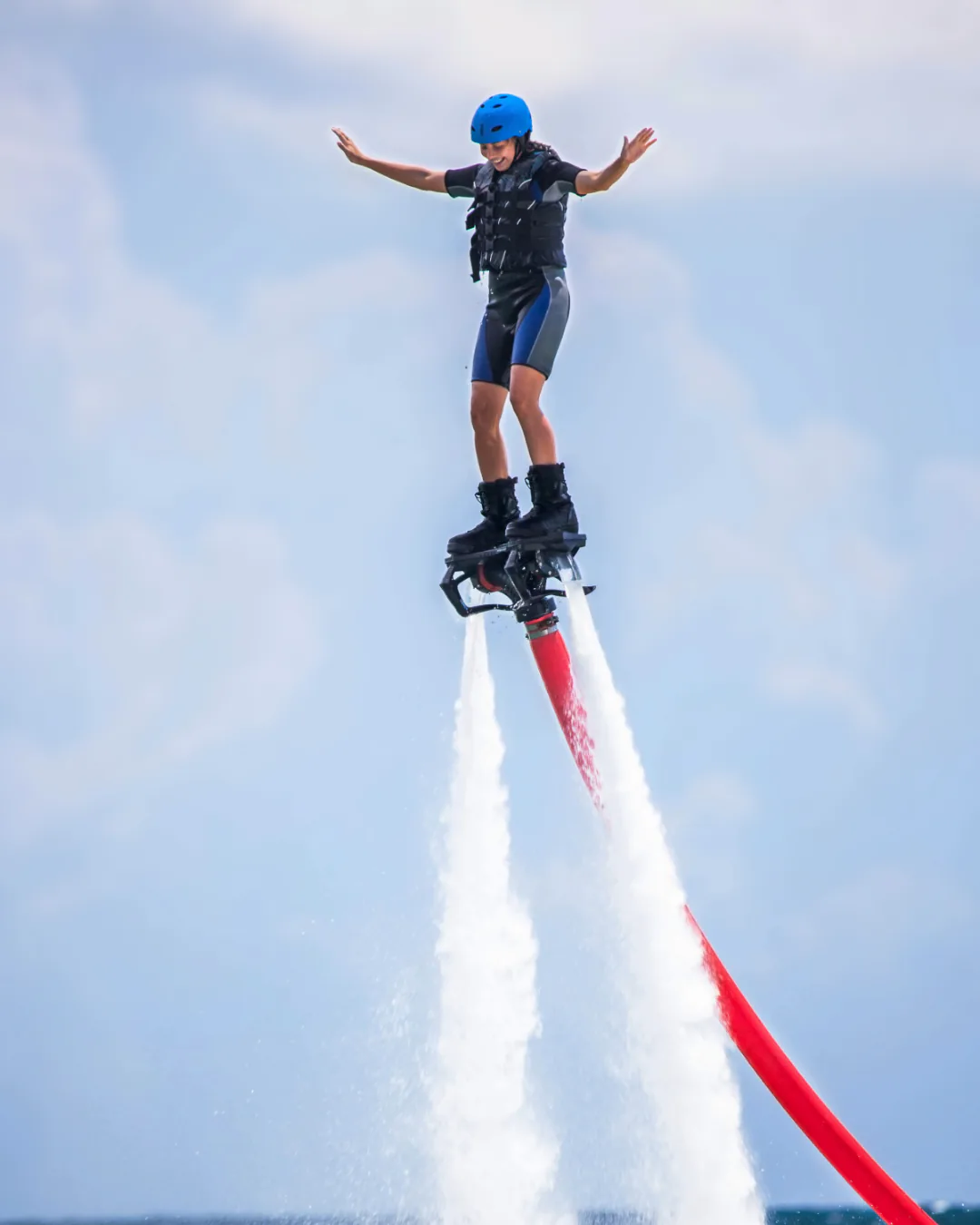 Helmeted first-time rider balancing upright on a Flyboard above the lake