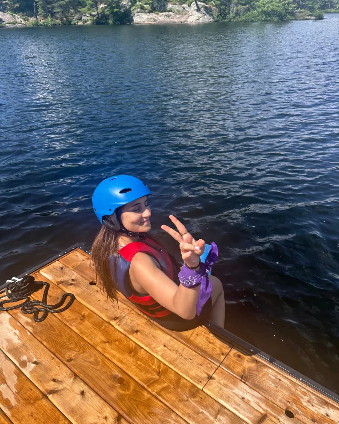 Helmeted first-time rider seated beside a wooden dock and making a peace sign