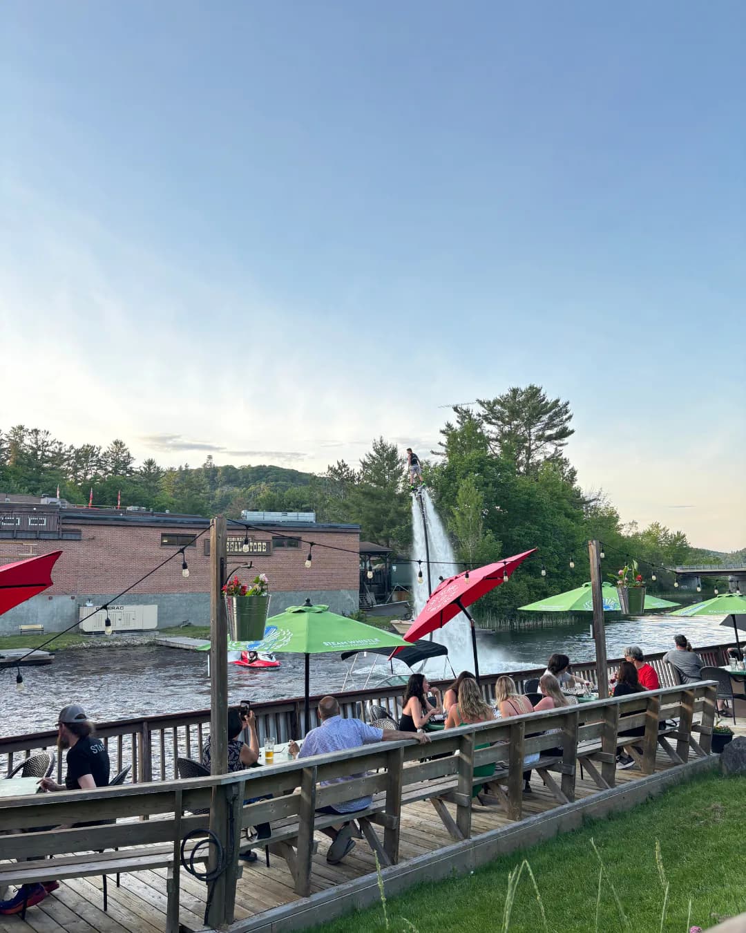 Flyboard performer rising above a Muskoka waterfront while patio guests watch