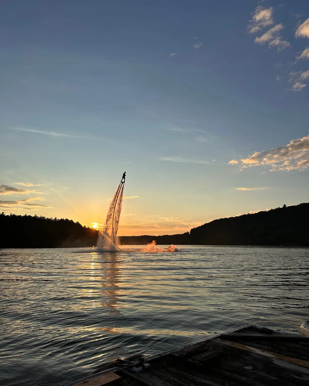 Flyboard rider rising above a quiet Ontario lake at sunset with a dock in the foreground