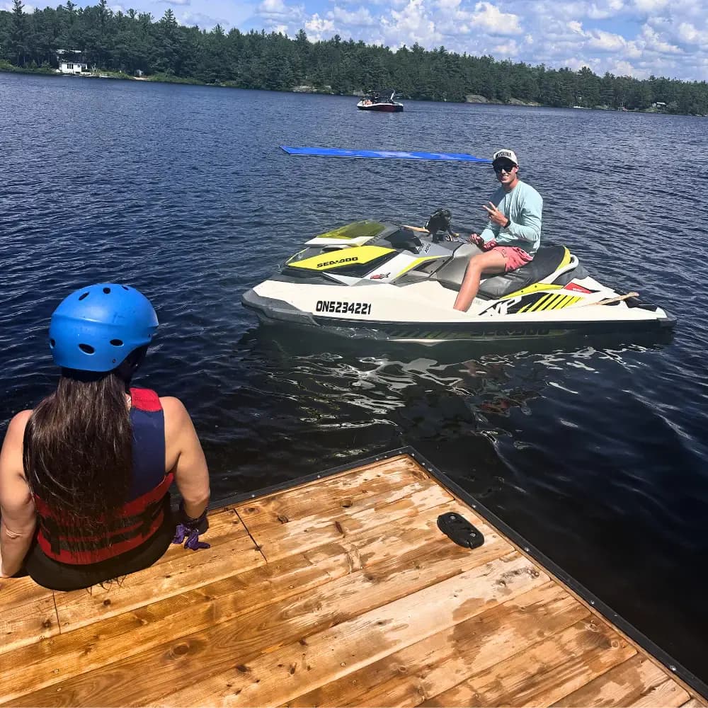 Helmeted participant seated on a dock facing an instructor on a Sea-Doo