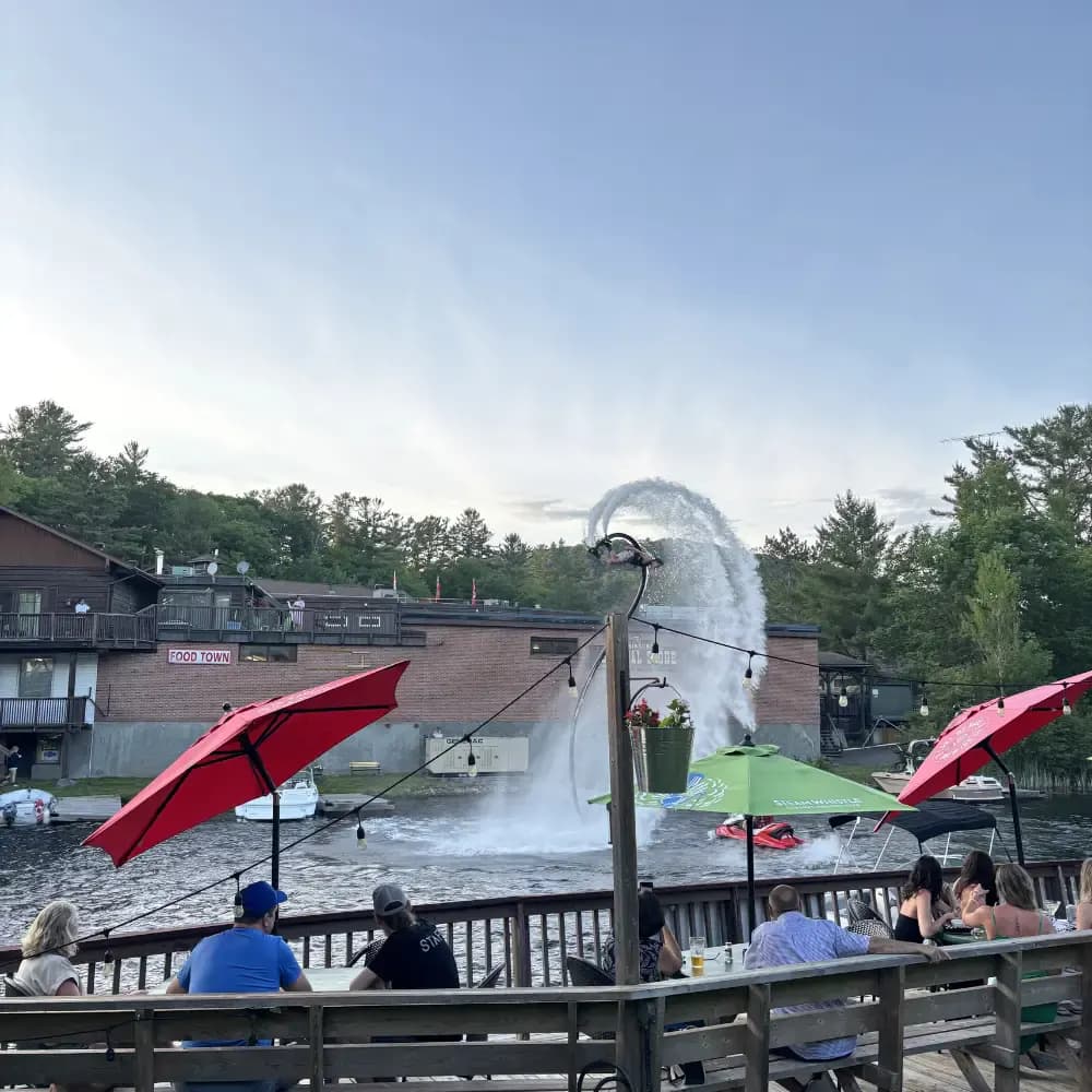 Flyboard performer making a spray arc beside a Lake of Bays waterfront patio